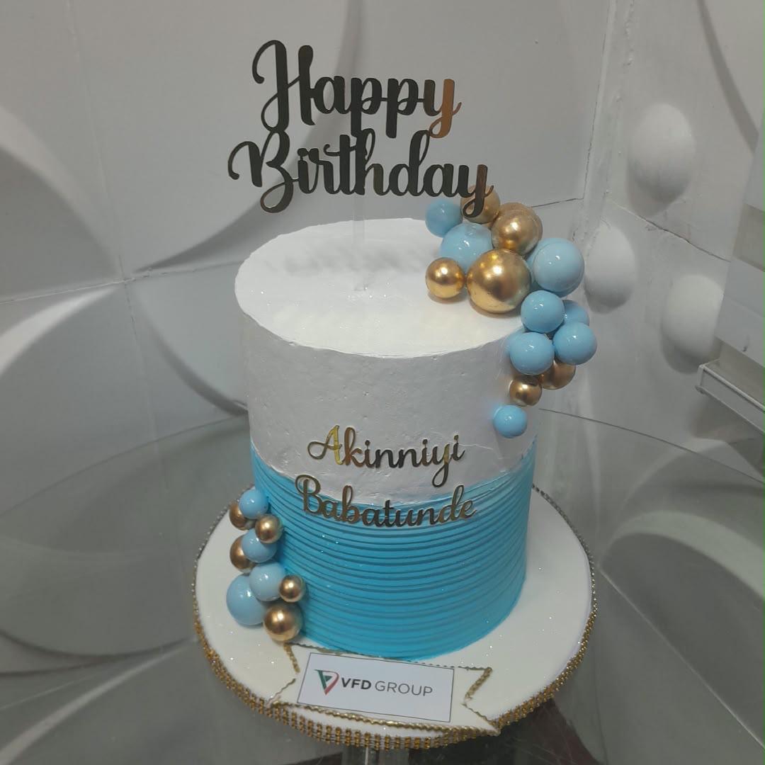 Blue ombre tiered cake decorated with blue and gold spheres.