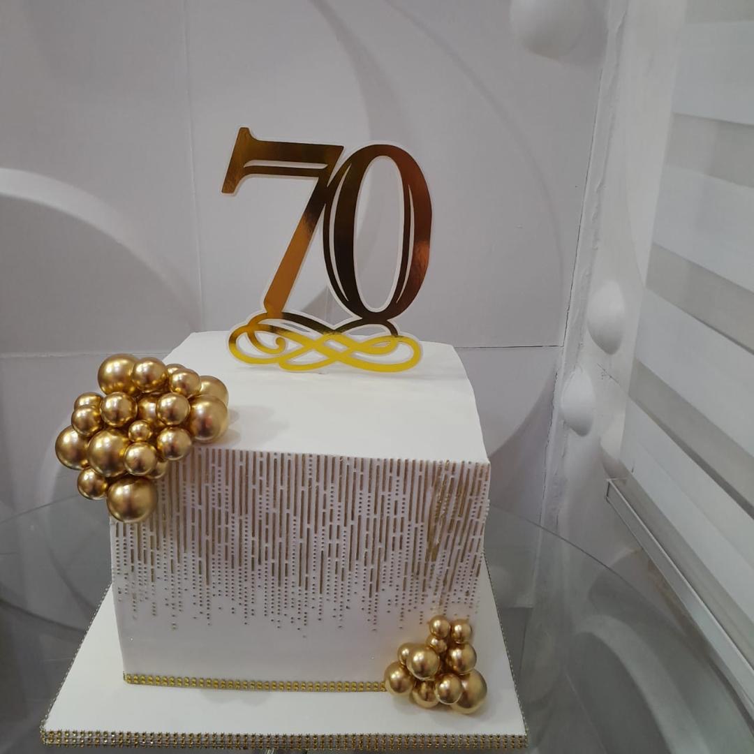 Square white-and-gold cake with a large 70 topper and gold spheres.