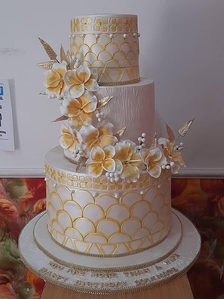 Three-tier cake with patterned icing and cascading flowers.