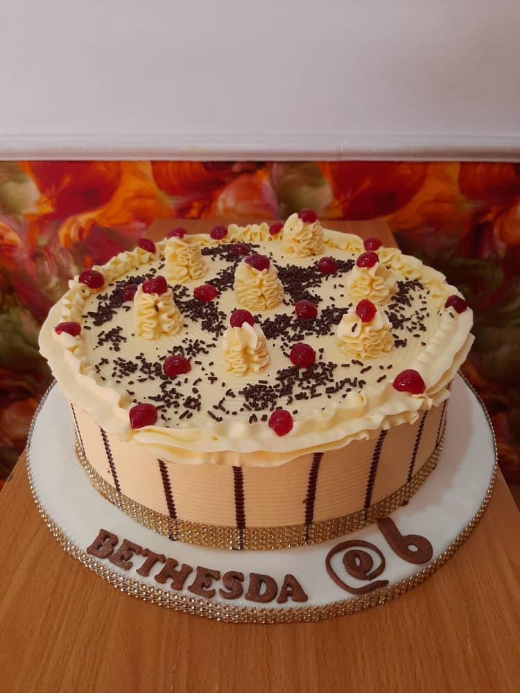 Round cake topped with cream and dark berries.