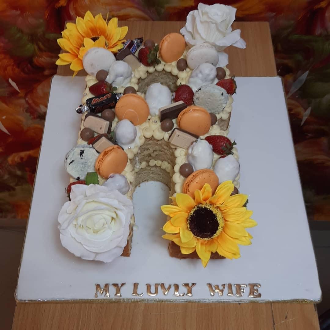 Number-shaped cake decorated with cream, strawberries, macarons, chocolates, and flowers.