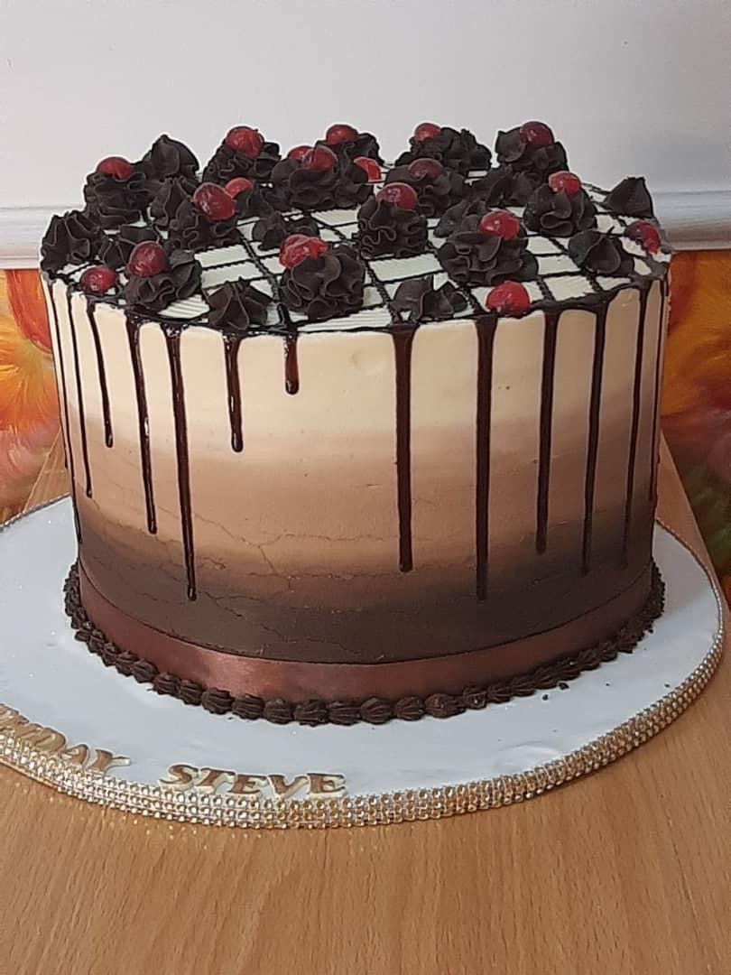Round chocolate-drip cake topped with mixed berries.