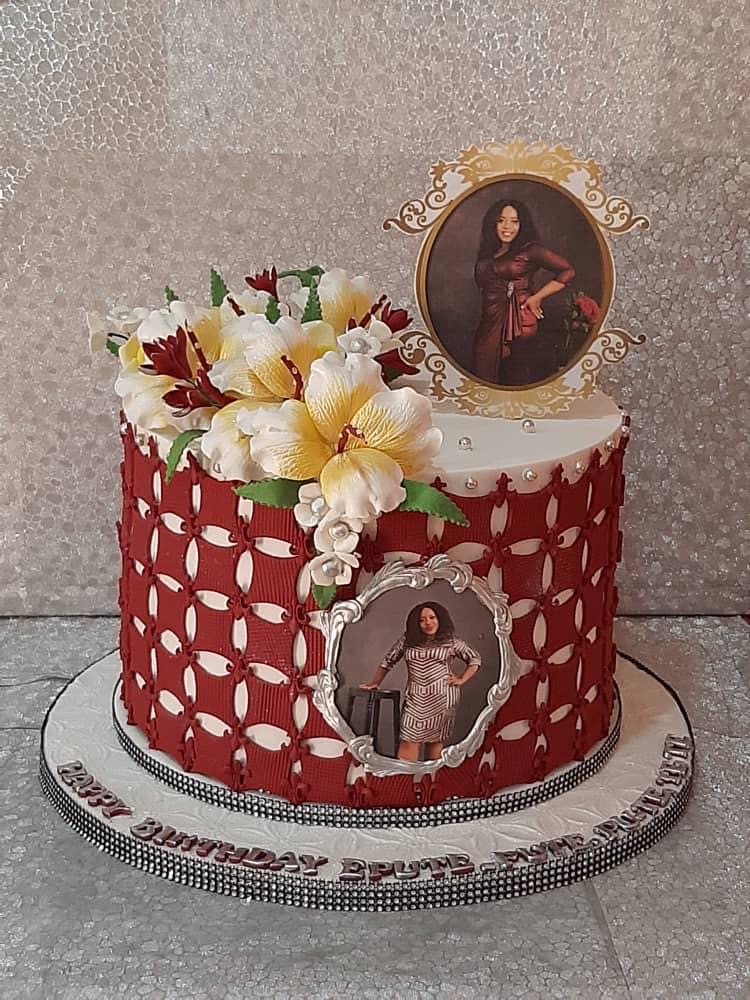 Red celebration cake with white lattice icing, flowers, and a photo topper.
