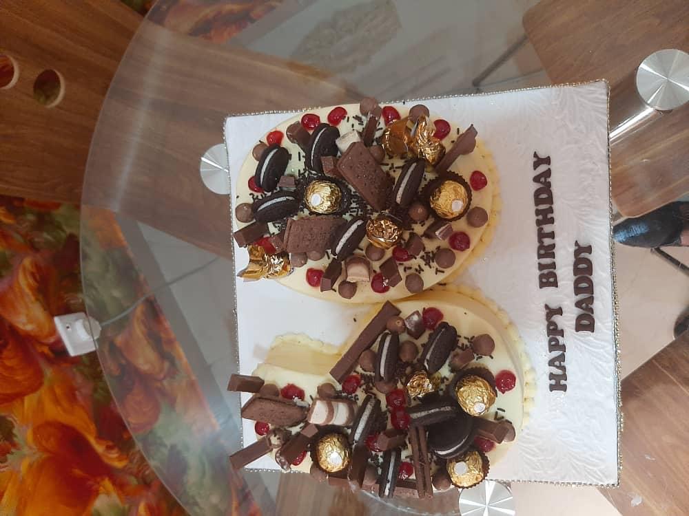 Two small decorated cakes on a rectangular board, topped with chocolates and treats.
