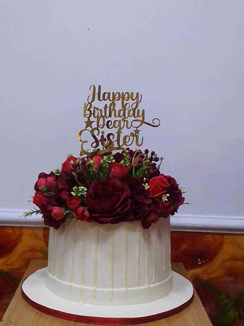 White cake topped with red roses and greenery.