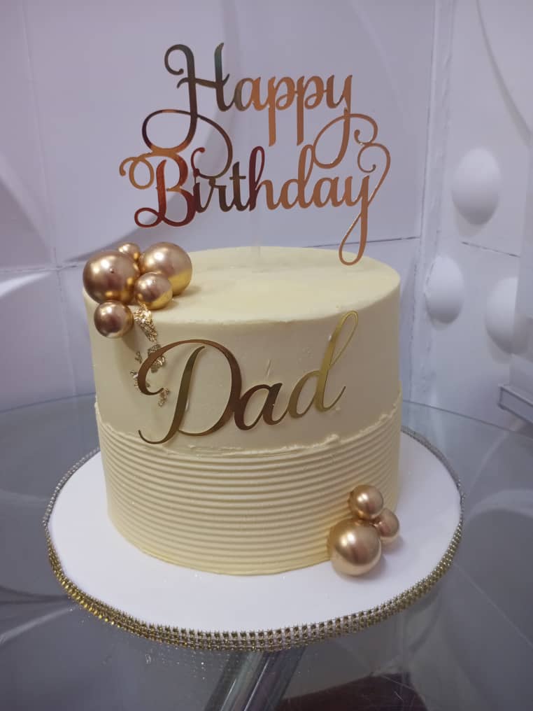 Ivory birthday cake with gold spheres and a Happy Birthday Dad topper.