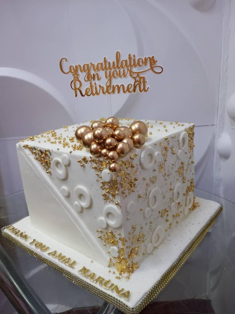 White-and-gold square cake with floral details and a Congratulations Retirement topper.