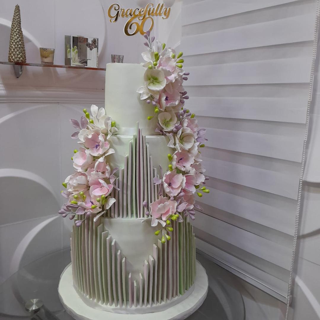 Tall white-and-silver tiered cake with cascading pale pink flowers.