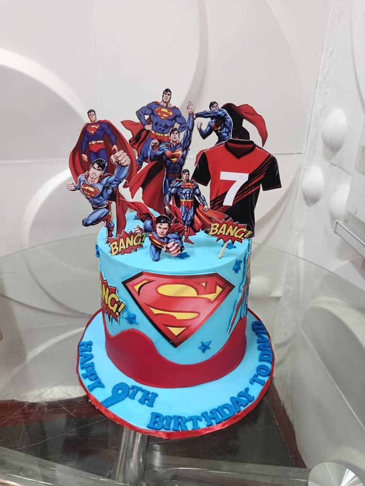 Blue superhero-themed cake with character figures.