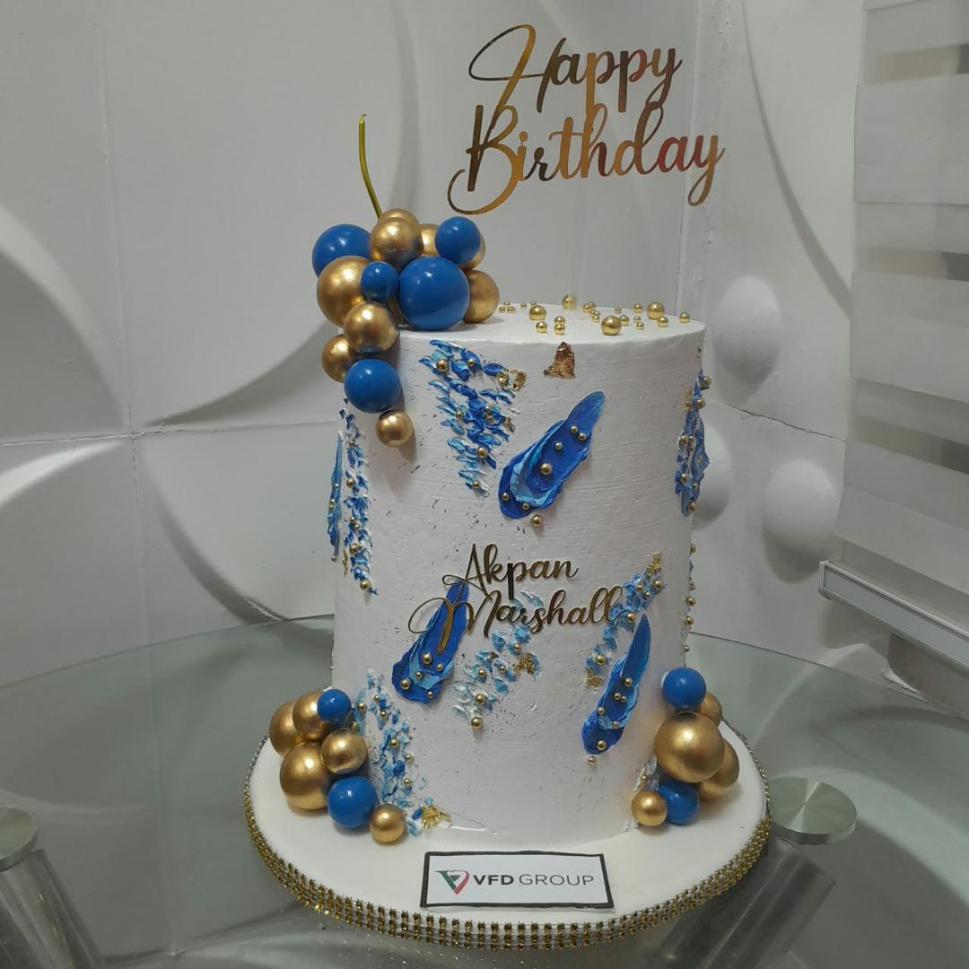 White birthday cake accented with blue and gold spheres.