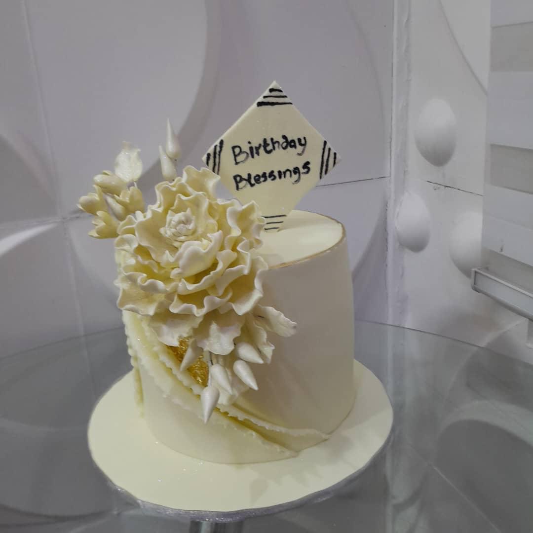 Ivory cake with cascading white flowers and a birthday topper.
