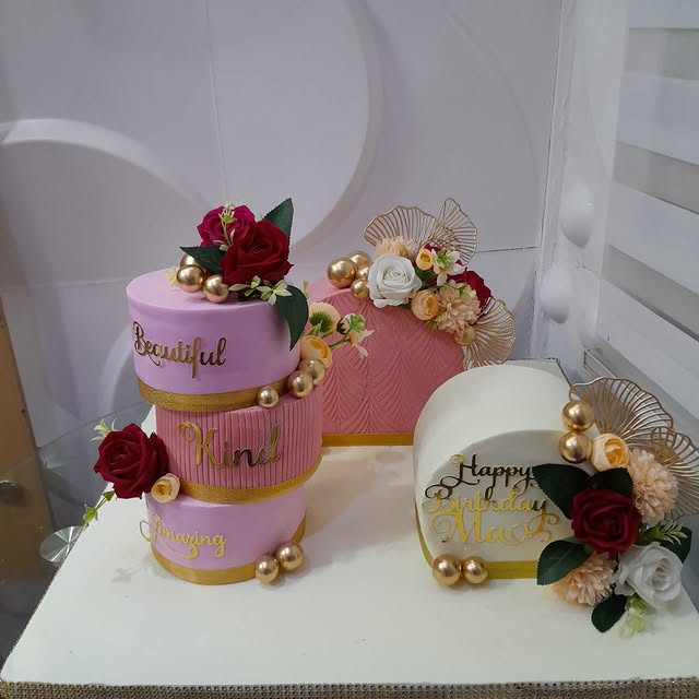 Three pastel celebration cakes with flowers, gold accents, and decorative lettering