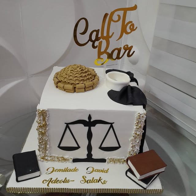 White Call to Bar cake with balance scales, gold trim, law books, and miniature legal props